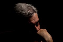 Contemplation, Fine art portrait of a man illuminated by dramatic light, lost in deep contemplation against a dark background.