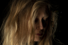 Silent Grace, Fine art portrait of a blonde woman looking downward, her face hidden, creating a timeless and emotional composition through light and shadow.