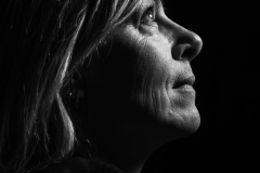 Toward the Light, Fine art black and white profile portrait of a woman looking toward the light against a dark background.