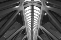 Black and white street photograph capturing a quiet modern staion, candid moment in public space.